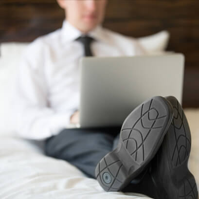 viajero de negocios usando laptop en cama de hotel o airbnb