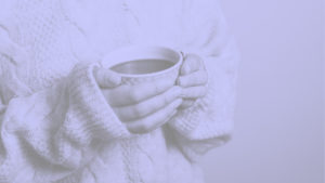 mujer vestida con sueter de invierno sosteniendo una taza de te